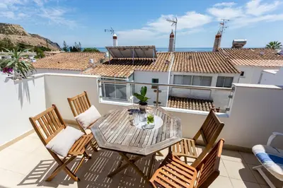 a patio with a table and chairs on a balcony at Mariners (3) - Bright and stylish apartment - 2 minute walk to the beach in Luz