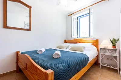 a bedroom with a wooden bed with a blue blanket at Casa Pedro Burgau in Burgau