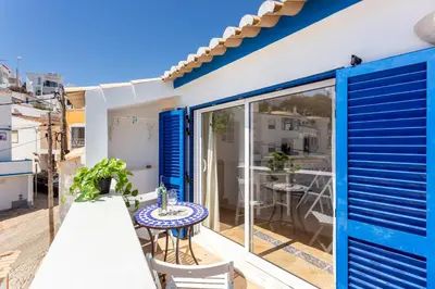 a balcony with blue shutters and a table and chairs at Casa Pedro Burgau in Burgau