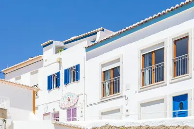 a white building with blue windows at Casa Pedro Burgau in Burgau