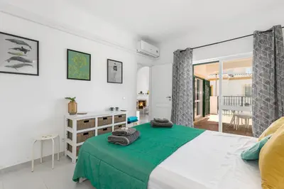 a bedroom with a bed with a green blanket at Cozy and sunny villa just some steps from the sea in Luz