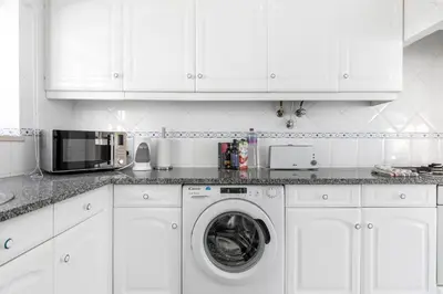 a white kitchen with a washing machine and a microwave at Cozy and sunny villa just some steps from the sea in Luz