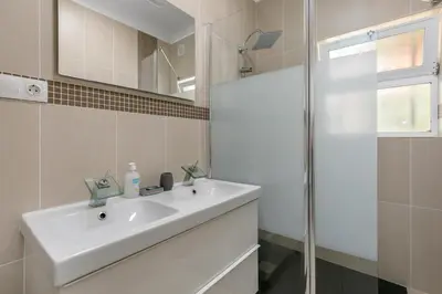a white bathroom with a sink and a shower at Cozy and sunny villa just some steps from the sea in Luz