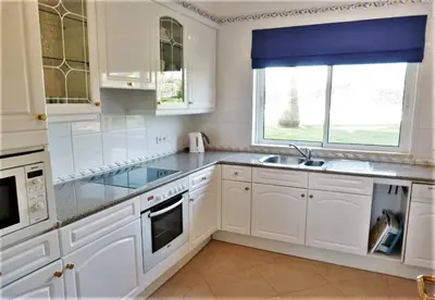 a kitchen with white cabinets and a sink and a window at Boavista 73 in Lagos