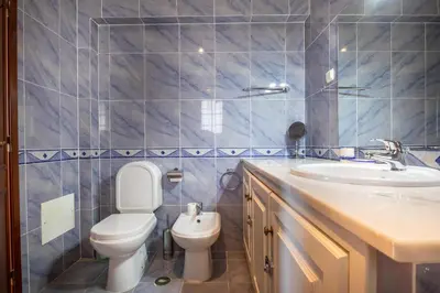 a blue tiled bathroom with a toilet and a sink at Villa Goshen in Lagos