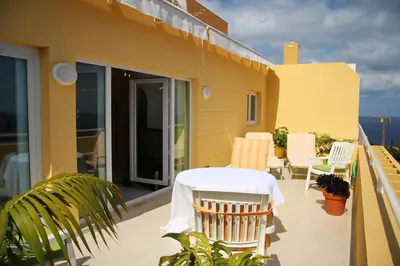 a patio with a table and chairs on a balcony at Villa Erika Madeira -Penthaus- in Caniço
