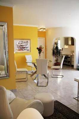 a living room with yellow walls and a table and chairs at Villa Erika Madeira -Penthaus- in Caniço