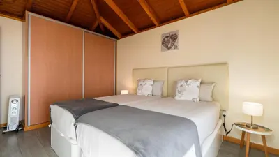 a bedroom with a large white bed and wooden ceilings at Casa da Felicidade by LovelyStay in Prazeres