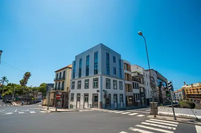 a tall white building on a city street with a street light at Zarco Apartments by Mercado Funchal in Funchal
