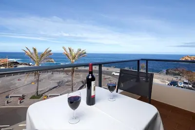 a table with two glasses of wine on a balcony at Perola Views Inn by Homie in Porto Moniz