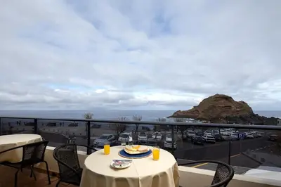 a table with a plate of food on a balcony at Perola Views Inn by Homie in Porto Moniz