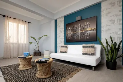 a living room with a white couch and a blue wall at Perola Views Inn by Homie in Porto Moniz