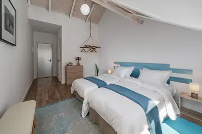 a bedroom with two beds with white and blue sheets at The Rum Inn in Calheta