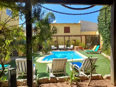 a backyard with a pool and chairs and a house at Casa Mestre Guesthouse in Vila do Bispo