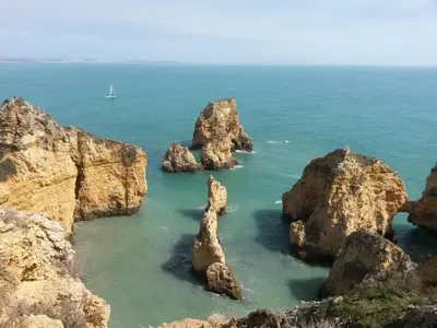 a group of rocks in the ocean with a boat at Casa Carmela in Burgau