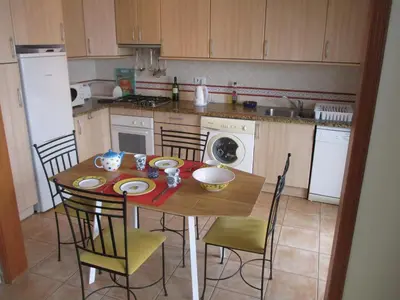 a kitchen with a wooden table with chairs and a kitchen with a stove at Casa Carmela in Burgau