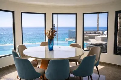 a dining room with a table and chairs and the ocean at Villa Sunset Avenue in Paul do Mar