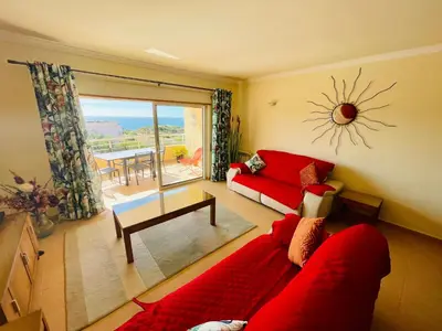 a living room with a red couch and a table at Vila das Acacias in Luz