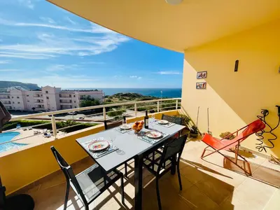 a table on a balcony with a view of the ocean at Vila das Acacias in Luz