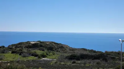 a small hill with the ocean in the background at Vila das Acacias in Luz
