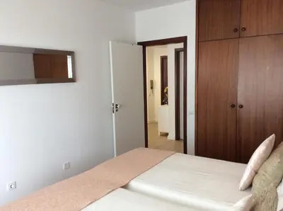 a bedroom with a white bed and a closet at Cosy Studio at Lido with Pool in Funchal