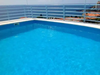 a large blue swimming pool on top of a building at Cosy Studio at Lido with Pool in Funchal