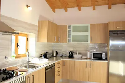 a kitchen with wooden cabinets and a stainless steel refrigerator at Quinta das Alfambras in Aljezur