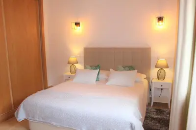 a bedroom with a large white bed with two lamps at Quinta das Alfambras in Aljezur