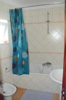a bathroom with a blue shower curtain and a sink at Casa Flora T1 - Vila do Bispo in Vila do Bispo