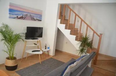 a living room with a staircase and a tv at Casa Flora T1 - Vila do Bispo in Vila do Bispo