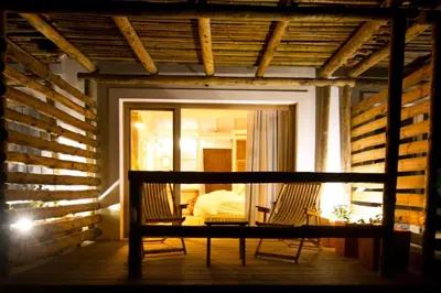 a porch of a house with two chairs and a bed at Hortas do Rio - Casa de Campo in Carrapateira