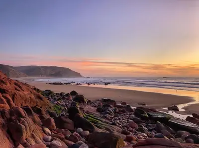a beach with rocks and the ocean at sunset at Hortas do Rio - Casa de Campo in Carrapateira