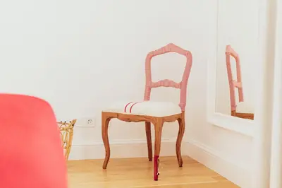 a wooden chair sitting in a room with a mirror at Apartamentos Ferreiros by Heart of Funchal in Funchal