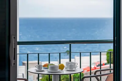 a table with cups and pastries on a balcony at Reis Magos IV by An Island Apart in Caniço