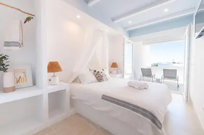 a white bedroom with a bed and a large window at Casa da Praia - Lagos in Lagos