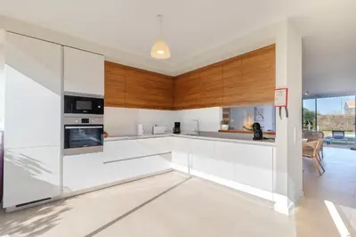 a kitchen with white counters and wooden cabinets at Villa Blue Sagres G in Sagres