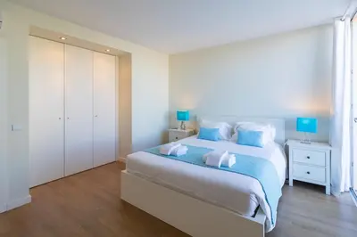 a white bedroom with a large bed with blue pillows at Villa Blue Sagres G in Sagres