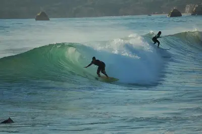 two people riding a wave on surfboards in the ocean at Villa Blue Sagres G in Sagres