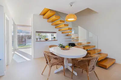 a dining room with a white table and chairs and a staircase at Villa Blue Sagres G in Sagres