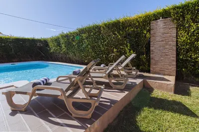 a row of lounge chairs next to a swimming pool at Villa Farol in Sagres