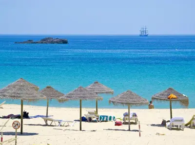 a beach with chairs and umbrellas and the ocean at Villa Farol in Sagres