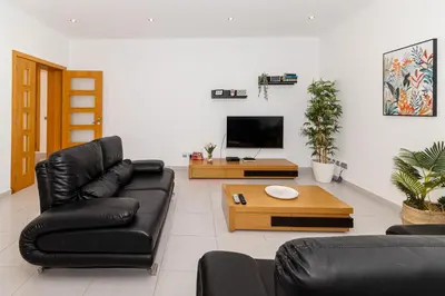 a living room with black leather furniture and a tv at Villa Farol in Sagres