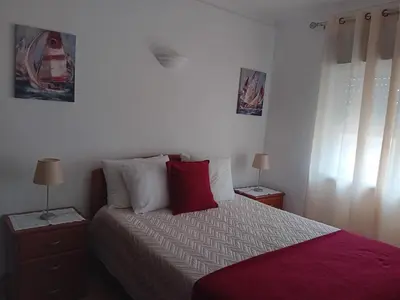 a bedroom with a bed with red pillows and two lamps at Burgau Mar in Burgau
