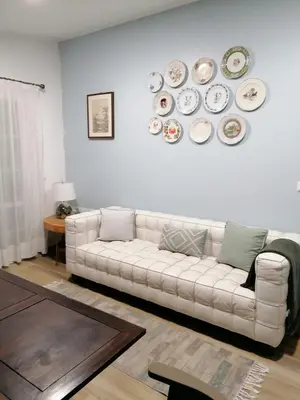 a living room with a white couch and plates on the wall at Casa da Bungavillia in Machico