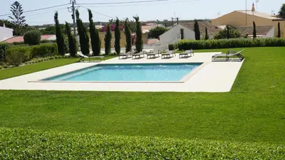 a swimming pool in a yard with chairs and trees at Apartamento 7 Mares in Sagres