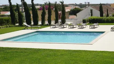 a swimming pool in a yard with chairs and trees at Apartamento 7 Mares in Sagres