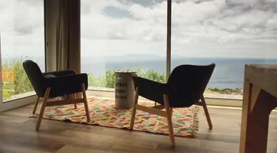 two chairs sitting in front of a large window at Quinta dos Artistas in Santa Cruz