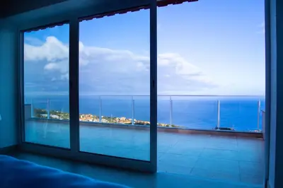 a bedroom with a view of the ocean from a window at Quinta dos Artistas in Santa Cruz
