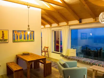 a living room with a table and a large window at Quinta dos Artistas in Santa Cruz