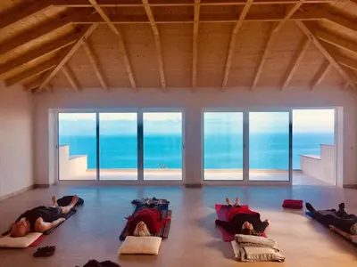 three people laying on the floor in a room with the ocean at Quinta dos Artistas in Santa Cruz
